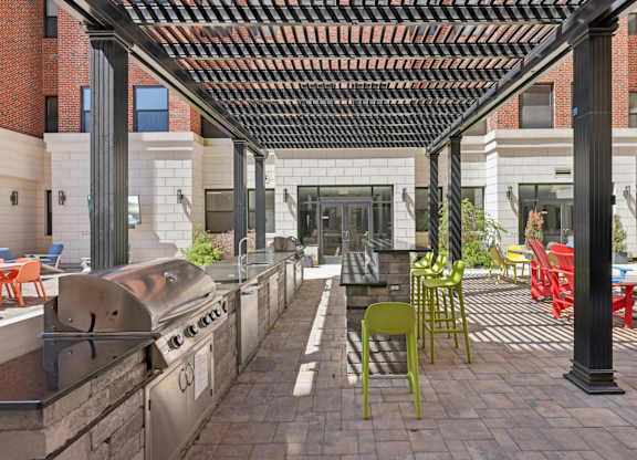 A patio with a grill and chairs.