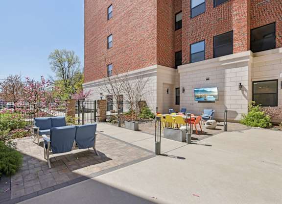 A brick building with a patio and chairs in front.