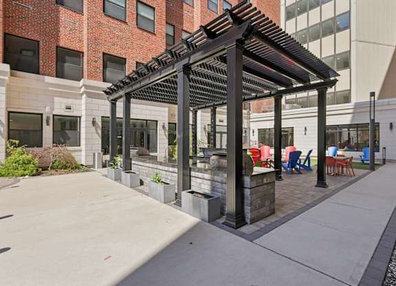 A patio with a black pergola and chairs.