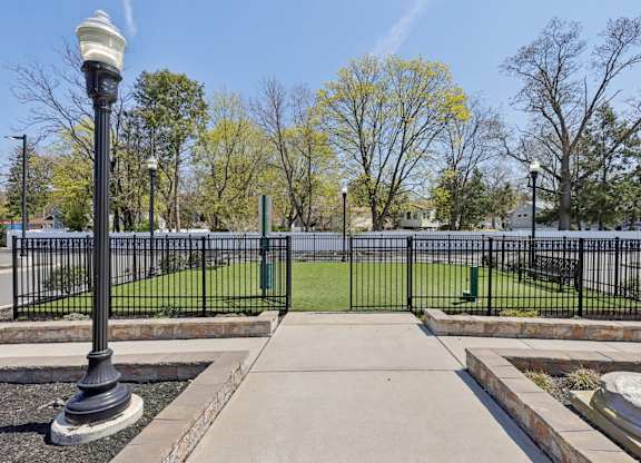 A black lamp post stands on a sidewalk in front of a black fence.