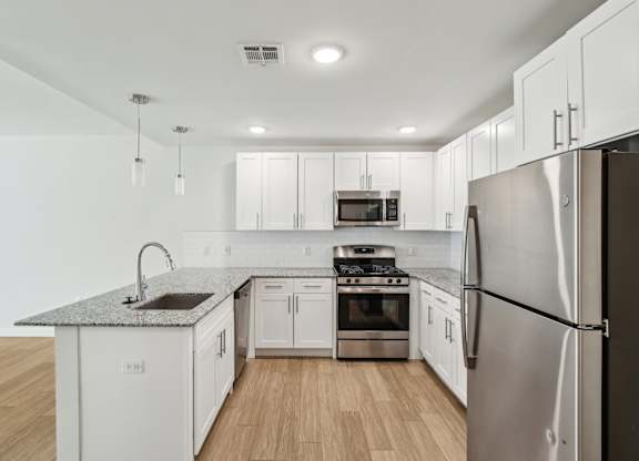 A modern kitchen with white cabinets and stainless steel appliances.