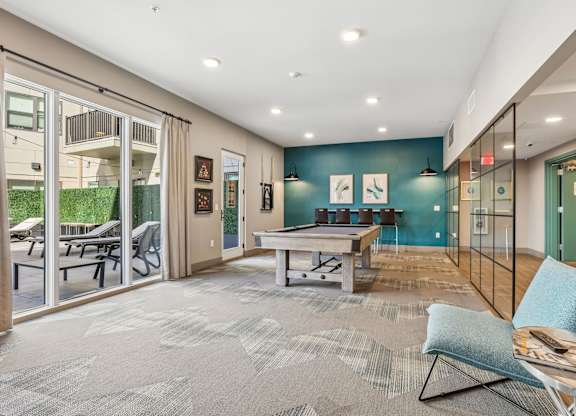 A spacious living room with a grey carpet and a blue chair.