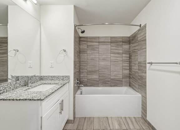 A white bathroom with a tub, sink, and mirror.