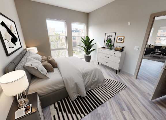 A bedroom with a bed, nightstand, and a plant at Crossroads 389 Apartments, Hackensack, NJ