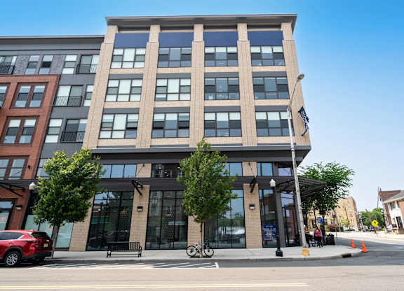 A modern building with a glass facade is situated on a street corner at Crossroads 389 Apartments, New Jersey, 07601