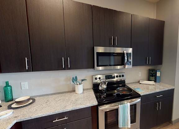 A kitchen with a stove top oven and microwave at Crossroads 389 Apartments, Hackensack