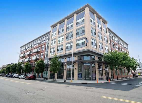 A modern multi-story building with a parking lot in front at Crossroads 389 Apartments, Hackensack, NJ