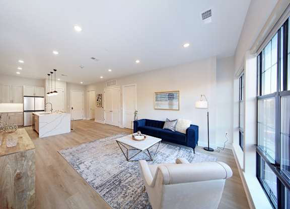 A spacious living room with a blue sofa and a rug.