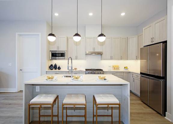 A kitchen with a white island and stools.