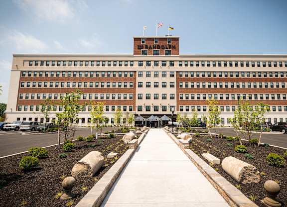 A large building with a flag on top and a walkway leading to the entrance.