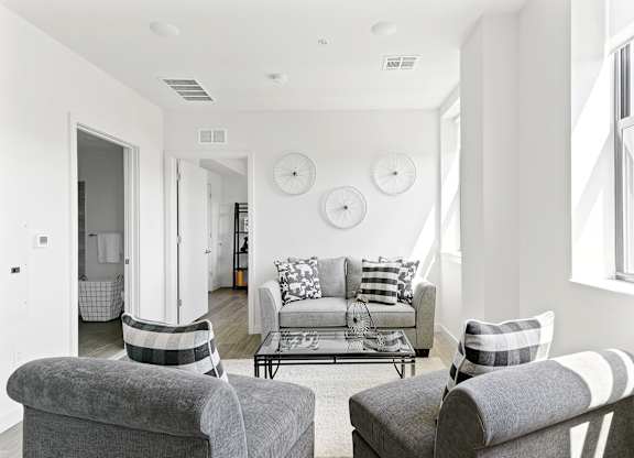 A living room with a grey couch and two grey armchairs.