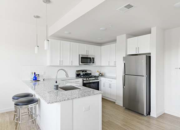 A modern kitchen with white cabinets and stainless steel appliances.