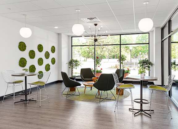 A room with a white table and chairs with a green wall decoration.