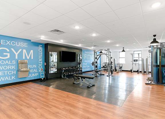 A gym with a variety of equipment and a wall with exercise motivation words.