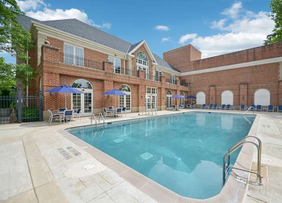A large swimming pool in front of a brick building.