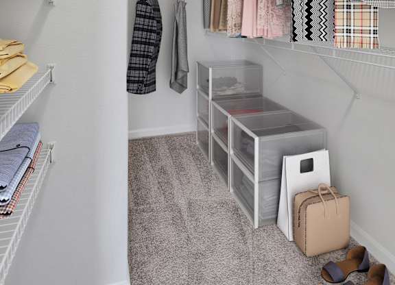 A small closet with clothes hanging and shoes on the floor.