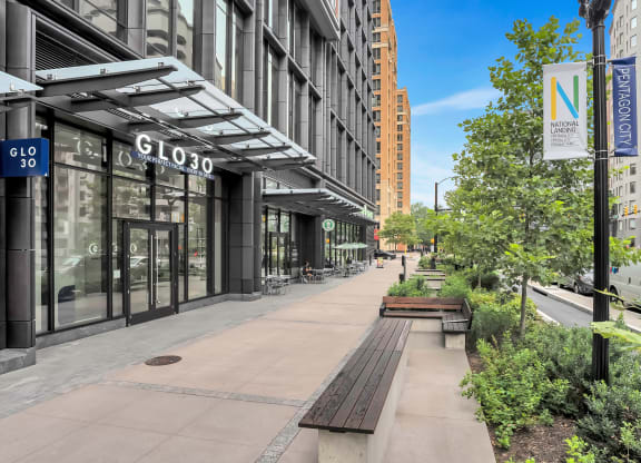 an empty sidewalk in front of a building with glass doors