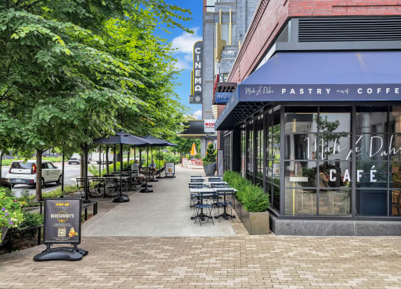a sidewalk outside of a coffee shop with tables and chairs