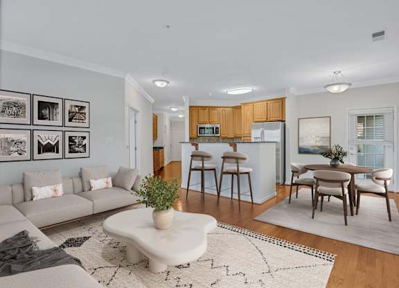 A modern living room with a grey sofa, a coffee table, and a dining table set up.