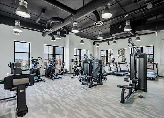 A gym with a variety of equipment including treadmills, weights, and exercise machines.