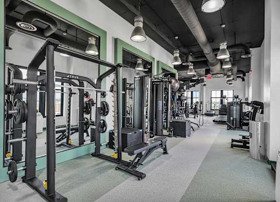 A gym with a variety of equipment including weight machines and free weights.