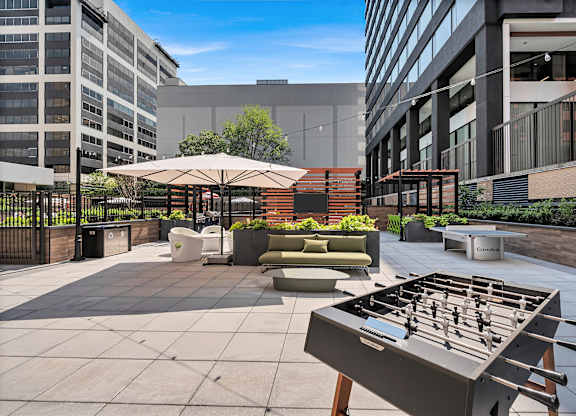 A foosball table is in the middle of a courtyard with a building in the background.