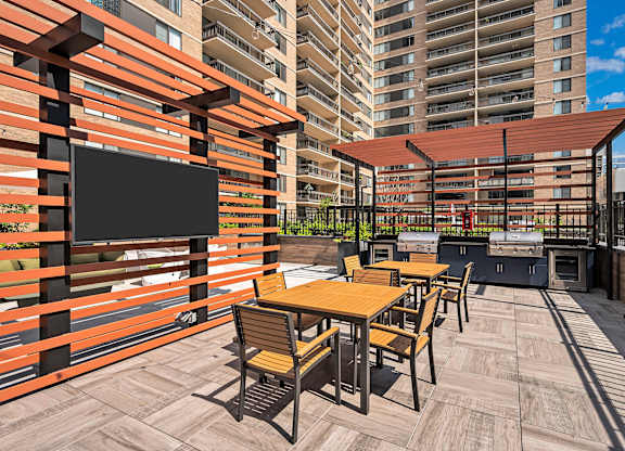 A patio with a table and chairs and a TV on a wall.