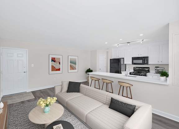 A living room with a couch, coffee table, and kitchen area in the background.