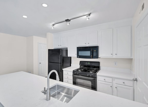 a kitchen with white cabinets and black appliances