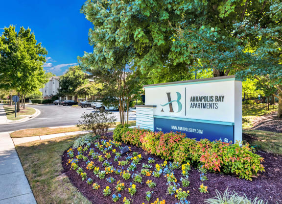 a sign for the headquarters of amours bay properties in front of trees and flowers