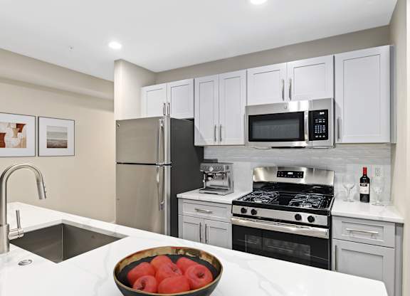A kitchen with a bowl of tomatoes on the counter.