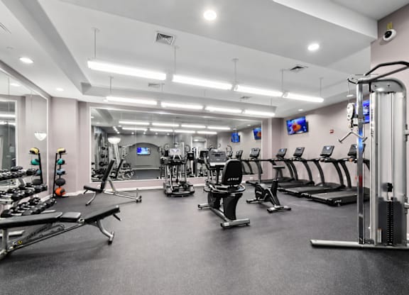 A spacious gym with various exercise equipment and mirrors on the wall.