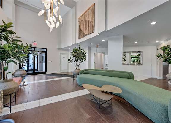 A modern living room with a long green couch and a wooden beam on the wall.