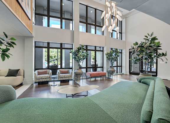 A large, modern living room with a green carpet and a chandelier.