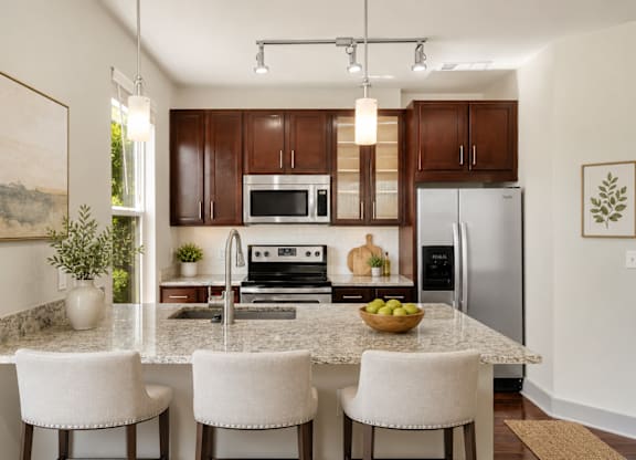 A kitchen with a granite countertop and white chairs.