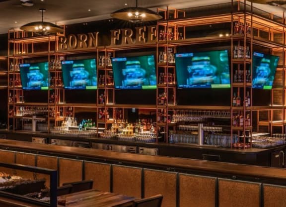 a bar with tvs on the wall and wooden tables and chairs