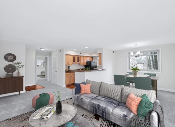 a living area with a couch coffee table and a kitchen in the background