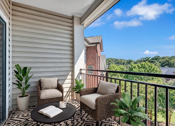 A balcony with a table, two chairs, and a potted plant.