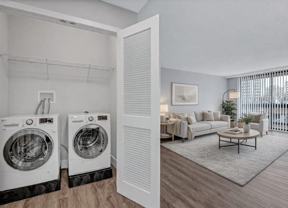 A laundry room with two washing machines and a living room with a sofa and coffee table.