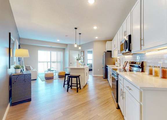 A modern kitchen with white cabinets and a wooden floor.