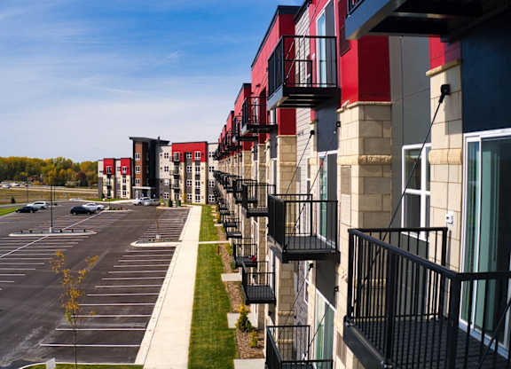 A parking lot in front of a row of apartment buildings.