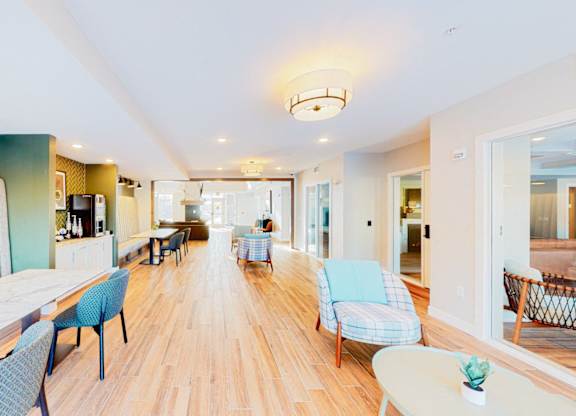 A long white table with blue chairs is in the middle of a room.