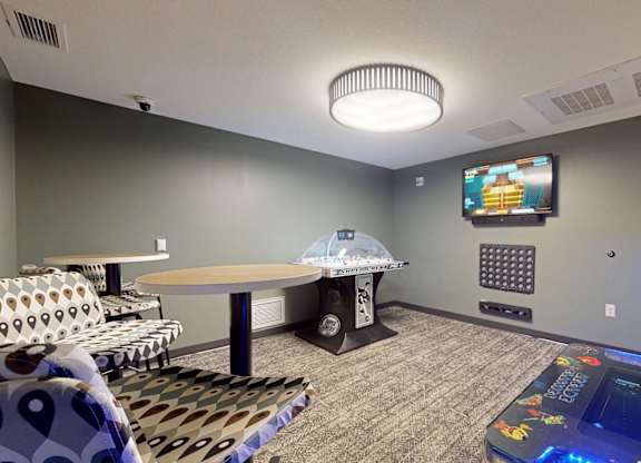 A room with a table, chairs, and a television mounted on the wall.