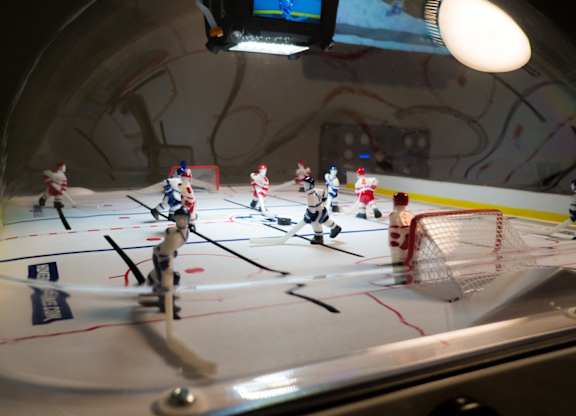 A group of small plastic people are playing a game of hockey on a table.
