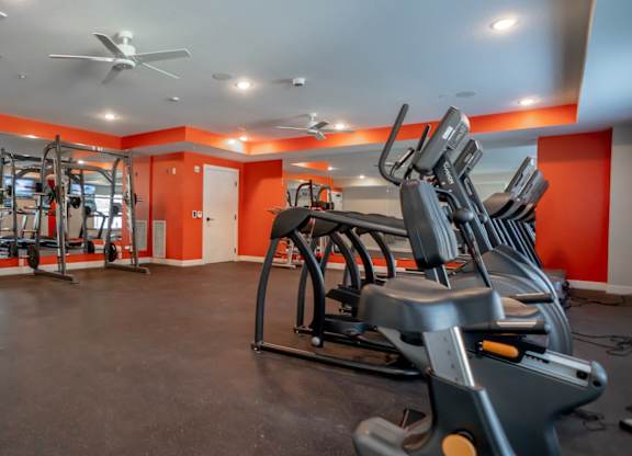 A gym with orange walls and a variety of exercise equipment.
