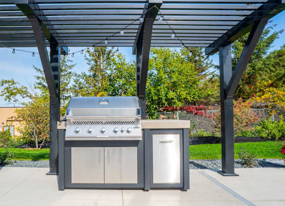 A modern outdoor kitchen setup with a grill, sink, and cabinet.