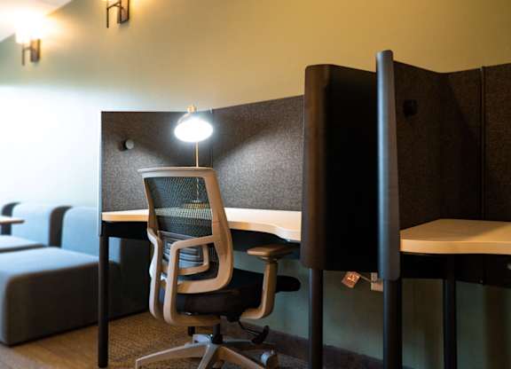 A room with a desk, chairs, and a couch.