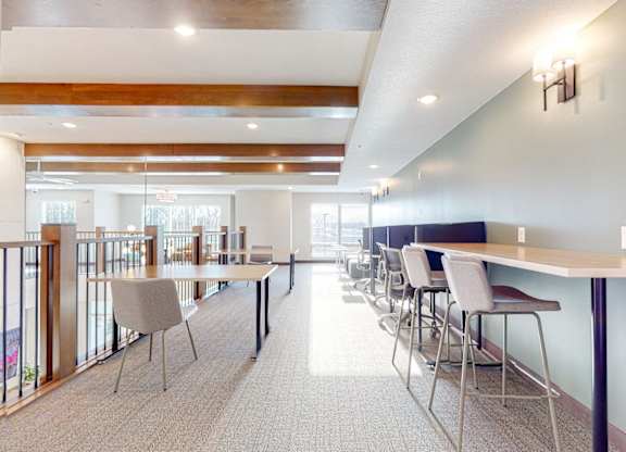 A long table with chairs is in a room with a lot of windows.