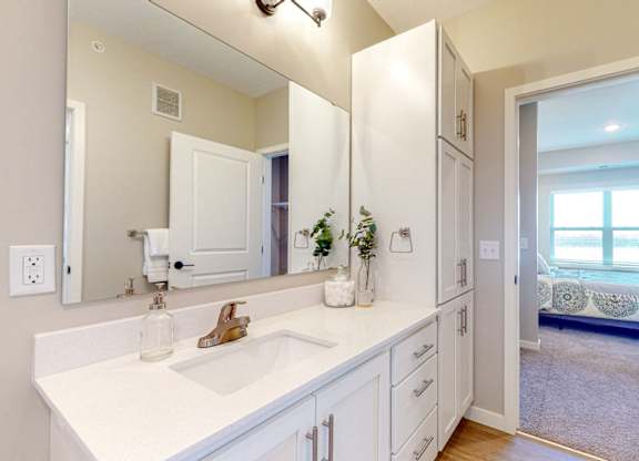 A bathroom with a white sink and mirror.