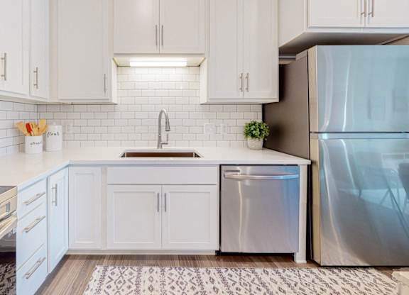 A kitchen with white cabinets and a stainless steel refrigerator.